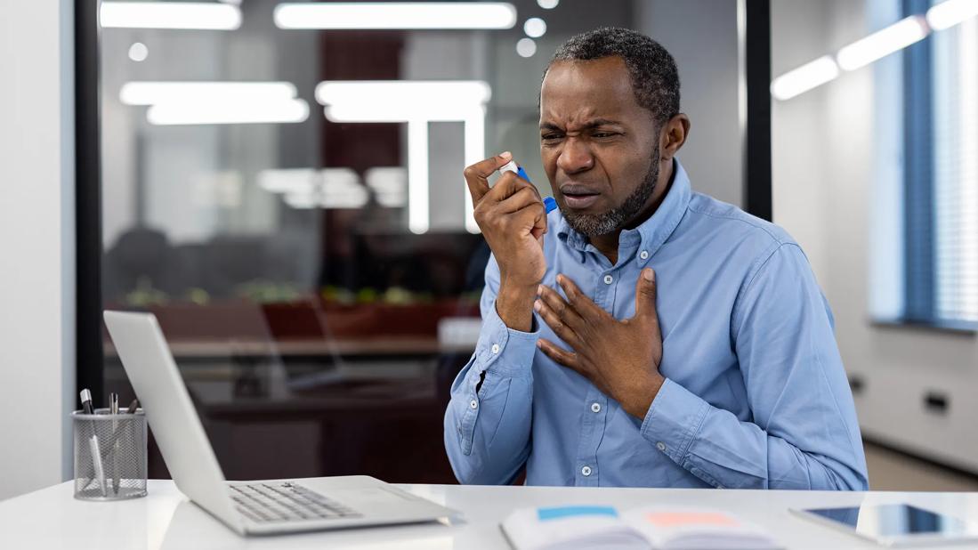 Person having an asthma attack at work, using inhaler