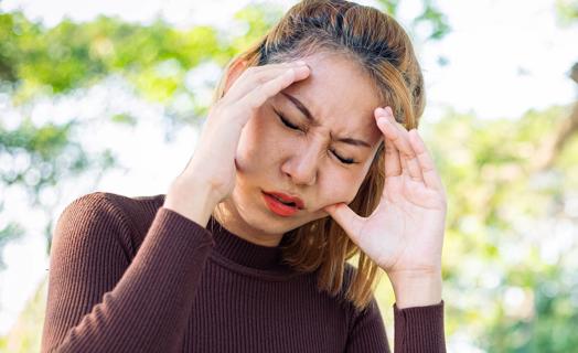 Person pressing on their face near their teeth and temples in pain