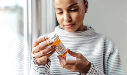 Person reading prescription medicine bottle