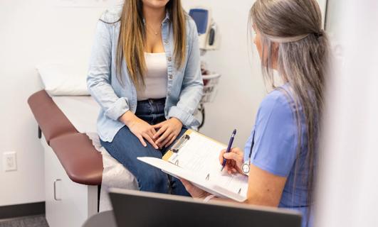 Female patient sitting on exam table discussing health with healthcare provider